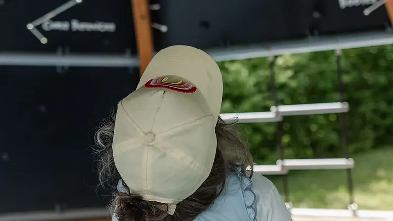Ein kleines Mädchen mit Basecap blickt in einem überdachten Spielbereich auf eine Wand mit Sternbildern.