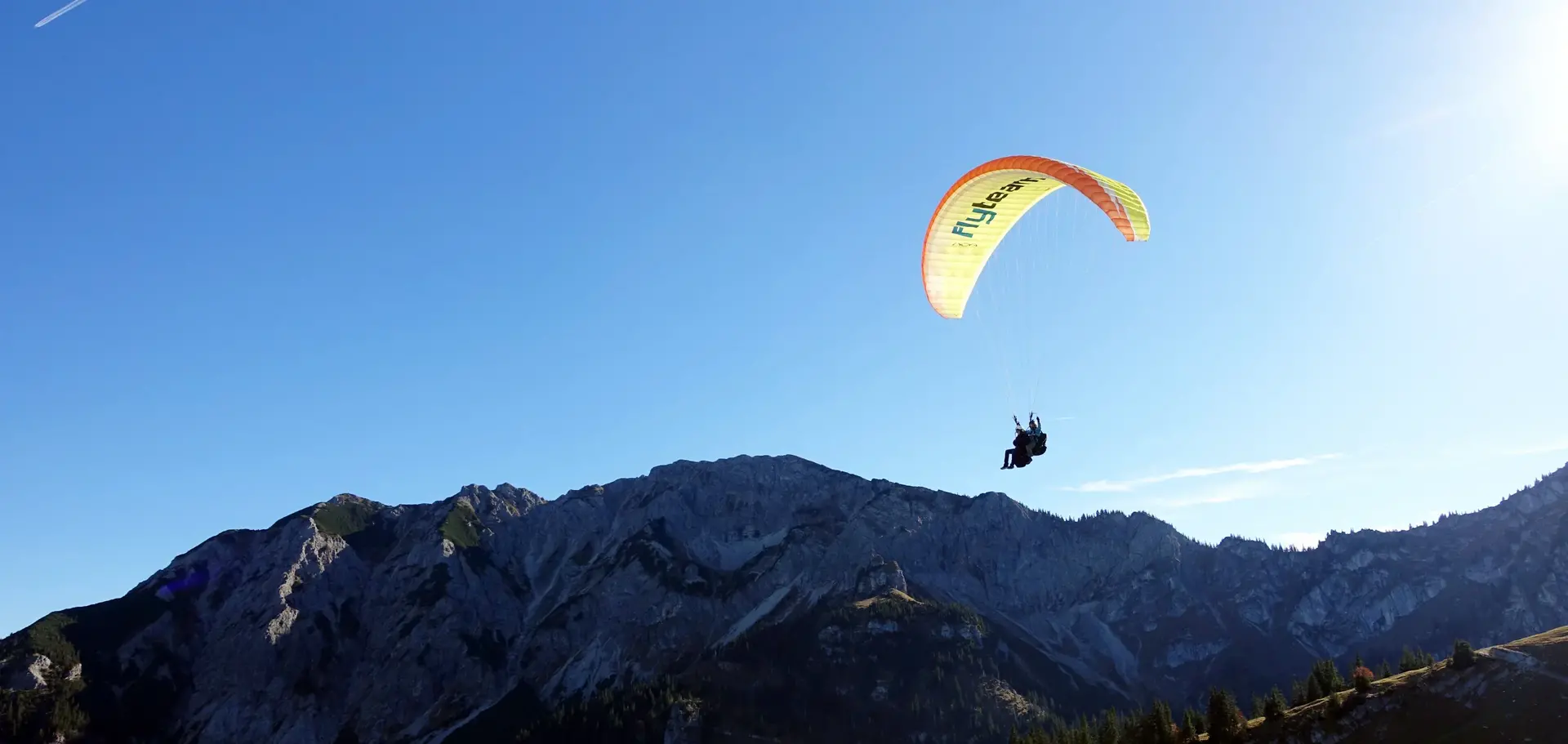 Tandemflug mit dem Gleitschirm am Breitenberg im Allgäu Ein Gleitschirmflieger schwebt vor einer beeindruckenden Bergkulisse.