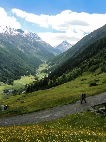 Blick von oben auf einem Wanderer in einer sonnigen Berglandschaft.