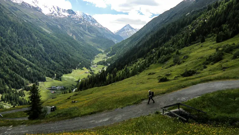 Blick von oben auf einem Wanderer in einer sonnigen Berglandschaft.