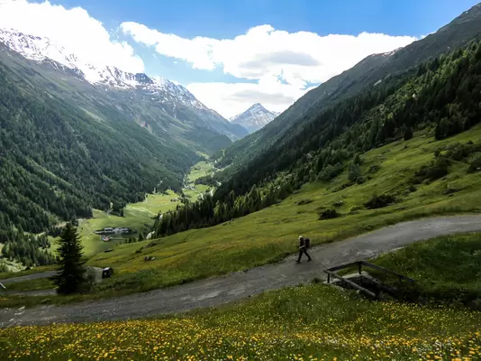 Blick von oben auf einem Wanderer in einer sonnigen Berglandschaft.