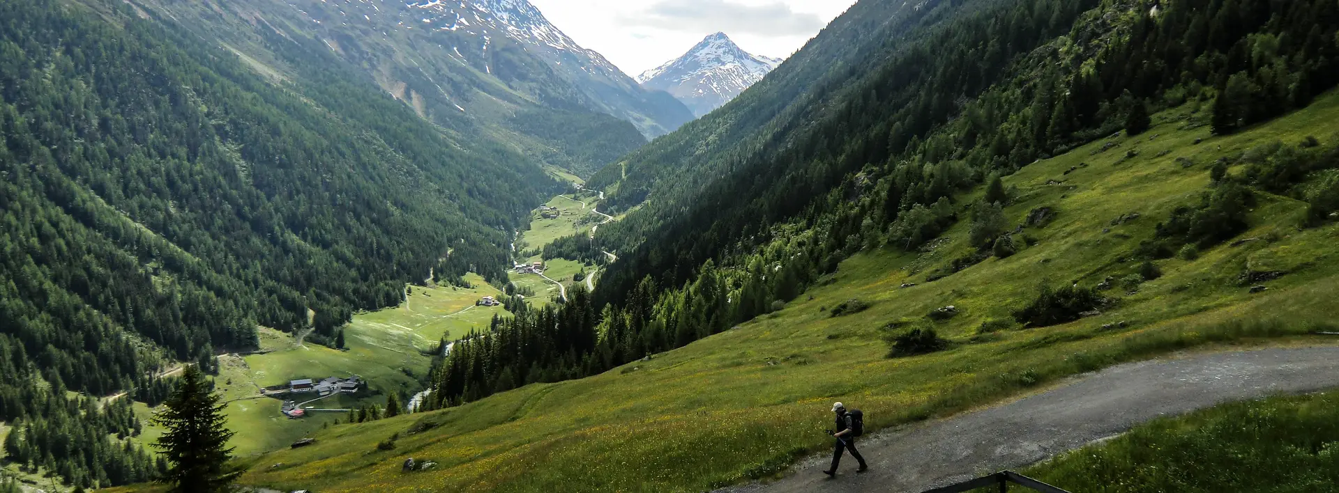 Blick von oben auf einem Wanderer in einer sonnigen Berglandschaft.