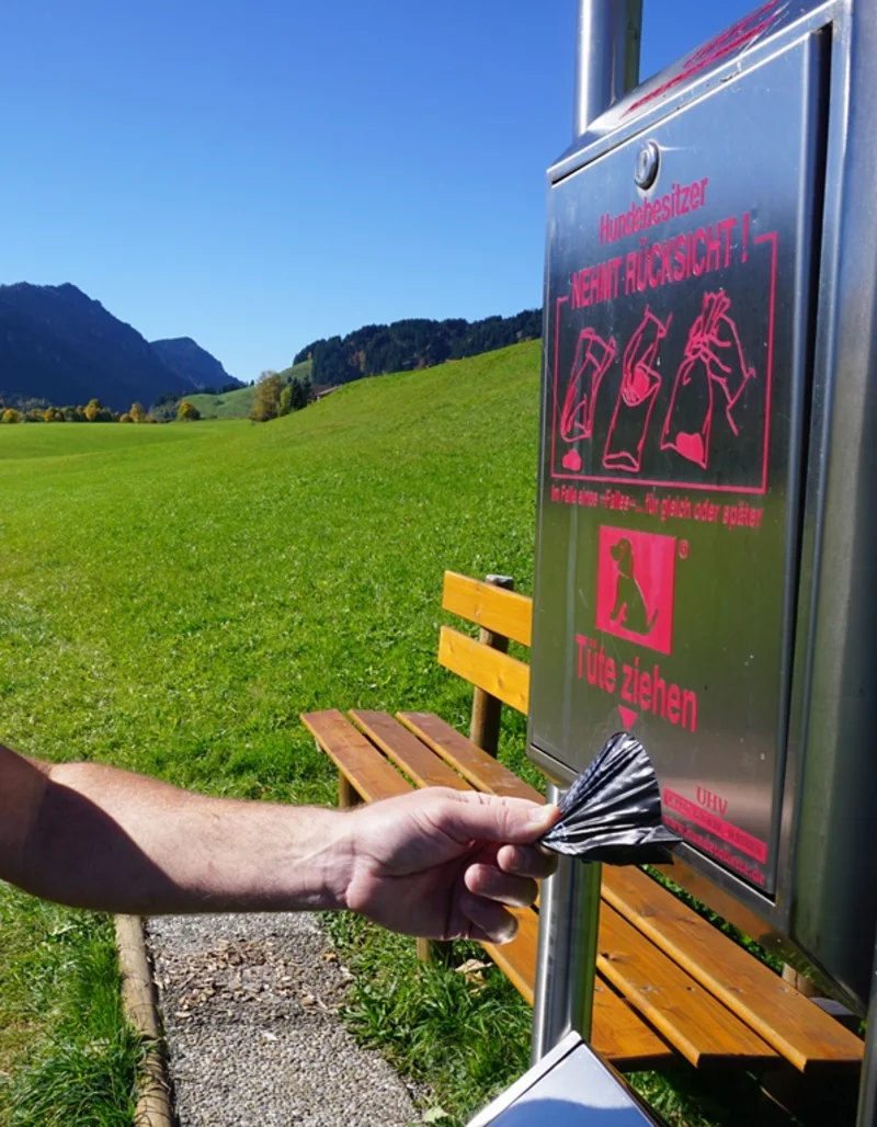 Ein Hundebesitzer zieht eine Tüte an einer Pfrontener Hundetoilette.