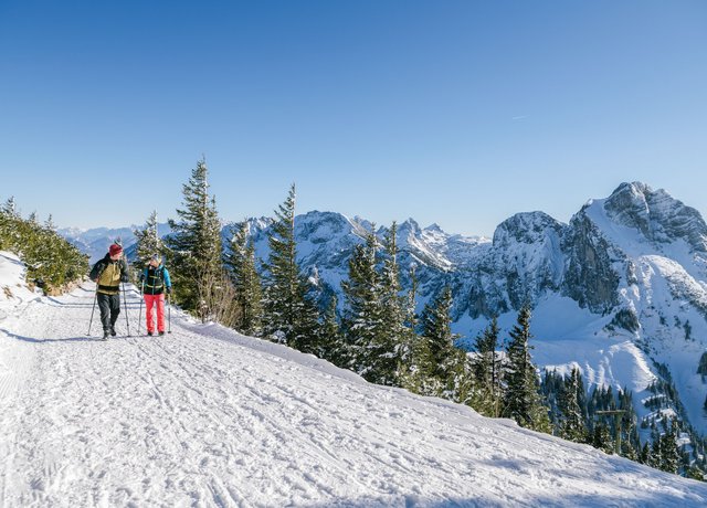Zwei Wanderer auf winterlichen Wegen mit einer tollen Bergkulisse.