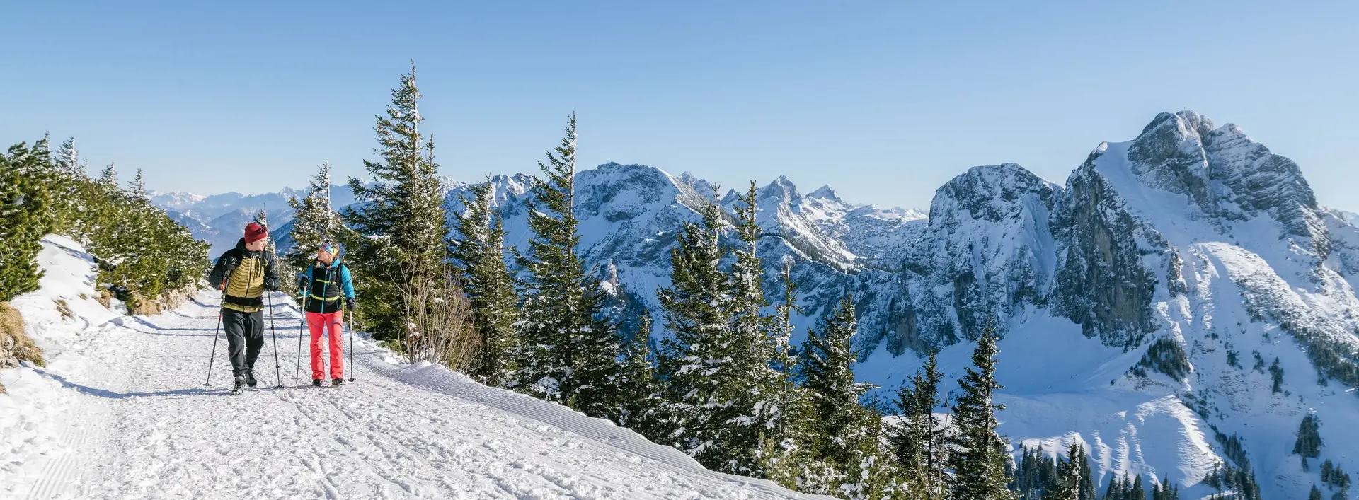 Zwei Wanderer auf winterlichen Wegen mit einer tollen Bergkulisse.