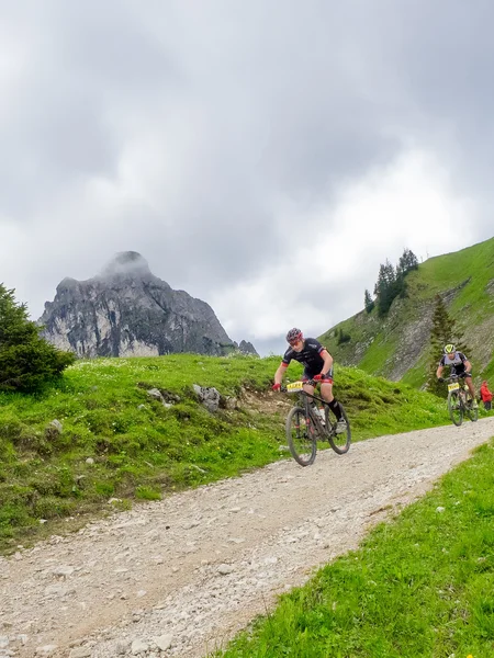Mountainbiker fahren einen schmalen Weg bergab durch die Allgäuer Berglandschaft.