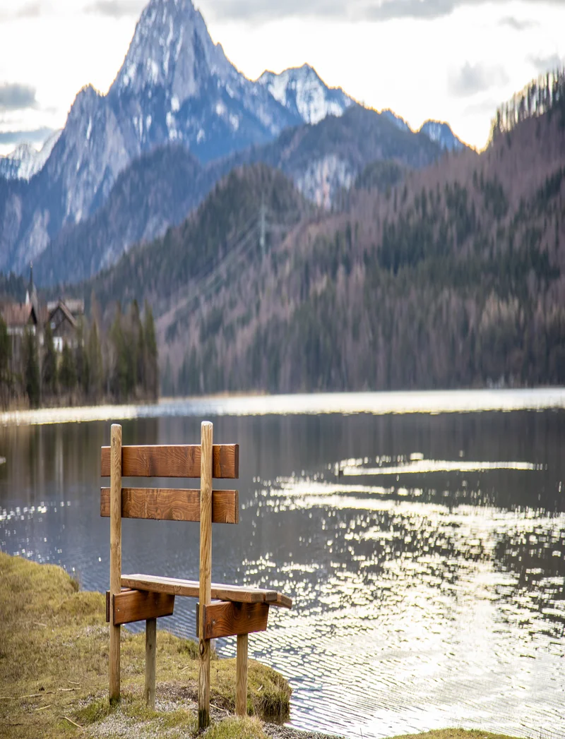 Eine Sitzbank vor dem Weißensee vor einer tollen Bergkulisse.