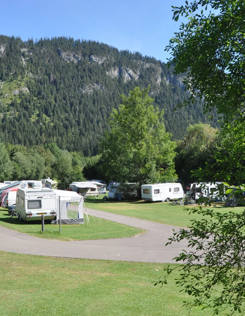 Camper auf dem Campingplatz in Pfronten mit Bergen im Hintergrund.