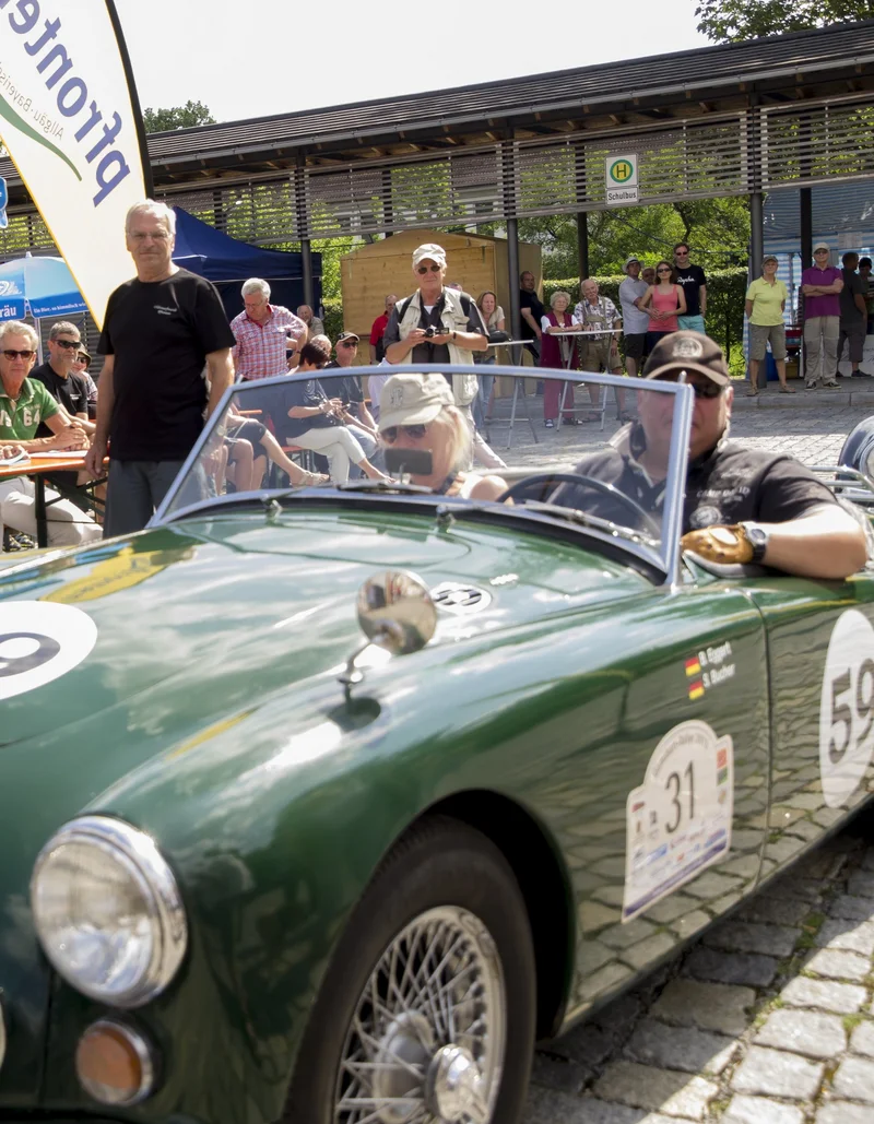 Ein Oldtimer wird von mehreren Personen beim Oldtimertreffen in Pfronten im Allgäu bestaunt.