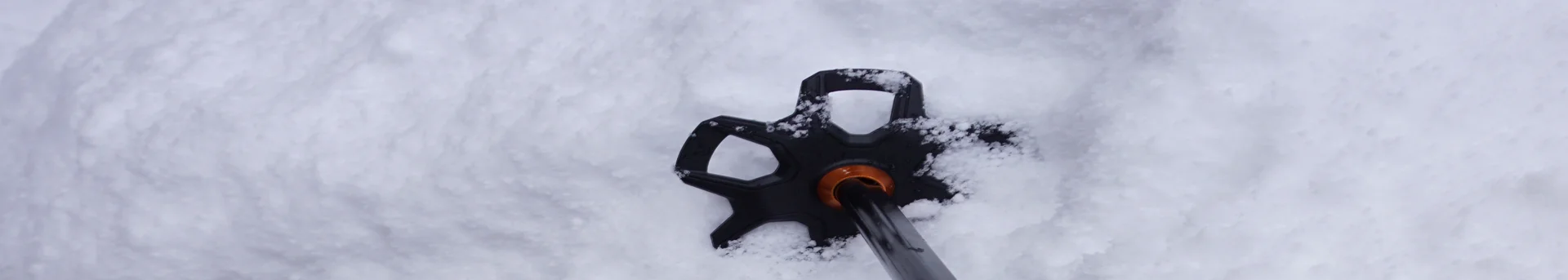 Ein Paar Skistöcke steckt im Schnee.