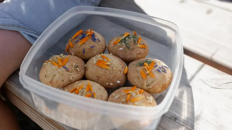 Muffins mit essbaren Blüten in einer Tupperdose.