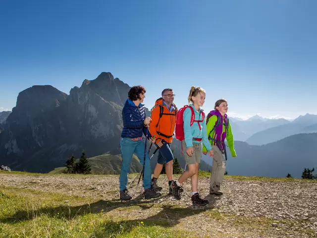 Eine Familie auf einem Wanderweg in einer beeindruckenden Bergkulisse.