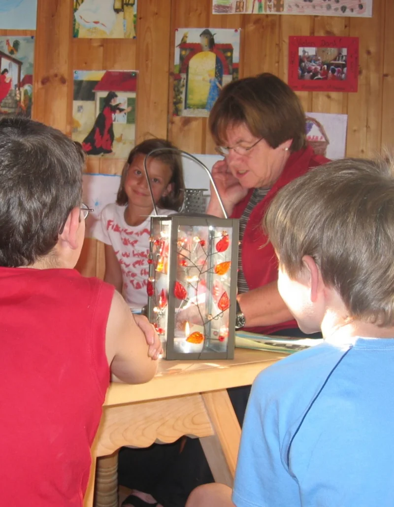 Eine Gruppe Kinder sitzt um einen Tisch bei einer Märchen- und Malstunde.