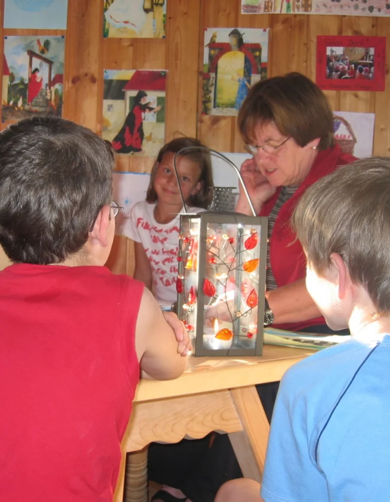 Eine Gruppe Kinder sitzt um einen Tisch bei einer Märchen- und Malstunde.