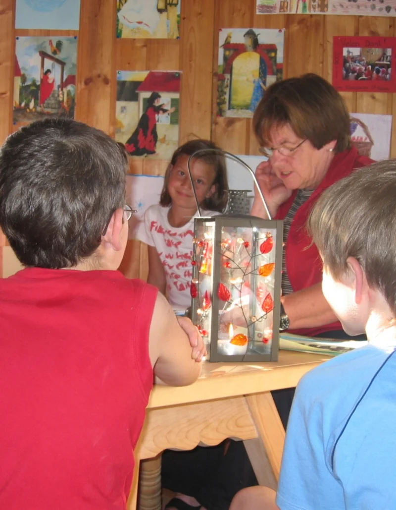 Eine Gruppe Kinder sitzt um einen Tisch bei einer Märchen- und Malstunde.