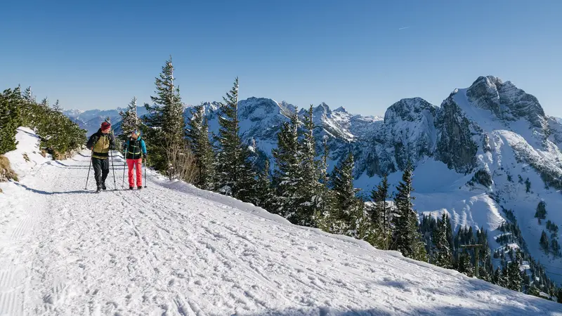 Zwei Wanderer auf winterlichen Wegen mit einer tollen Bergkulisse.