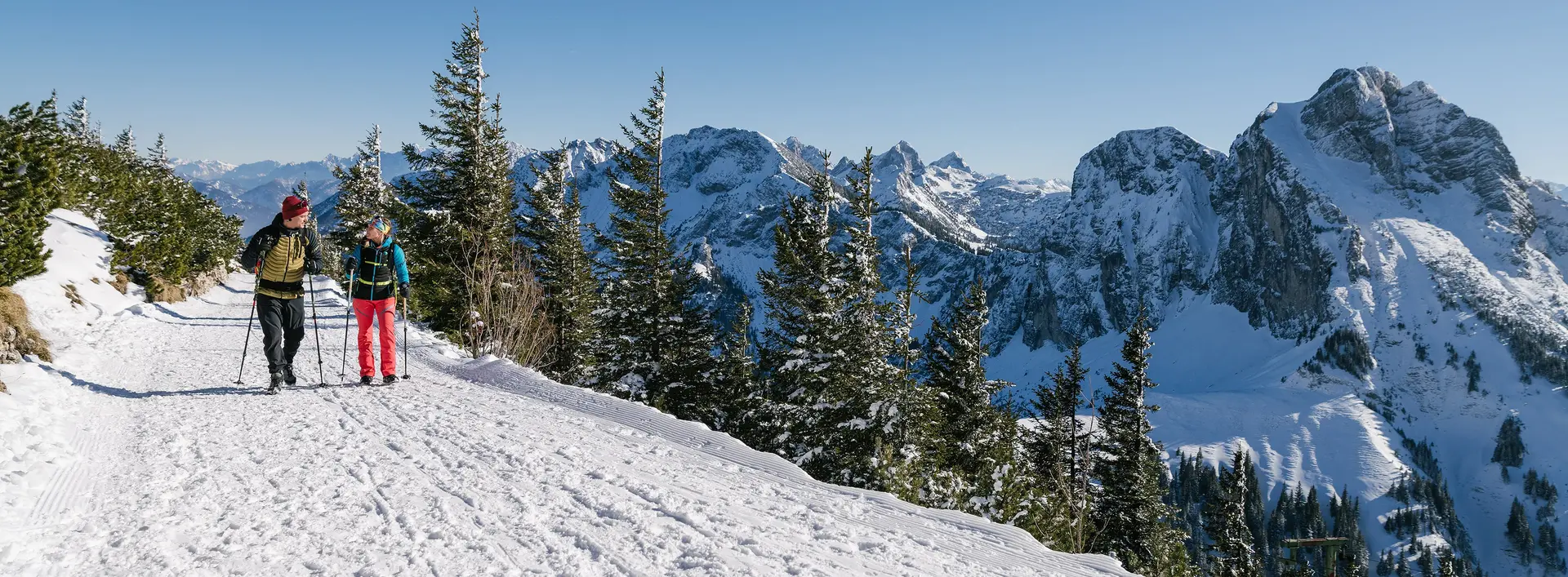 Zwei Wanderer auf winterlichen Wegen mit einer tollen Bergkulisse.