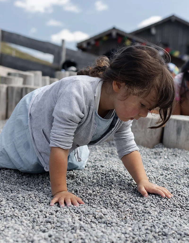 Ein Mädchen spielt im Kies.