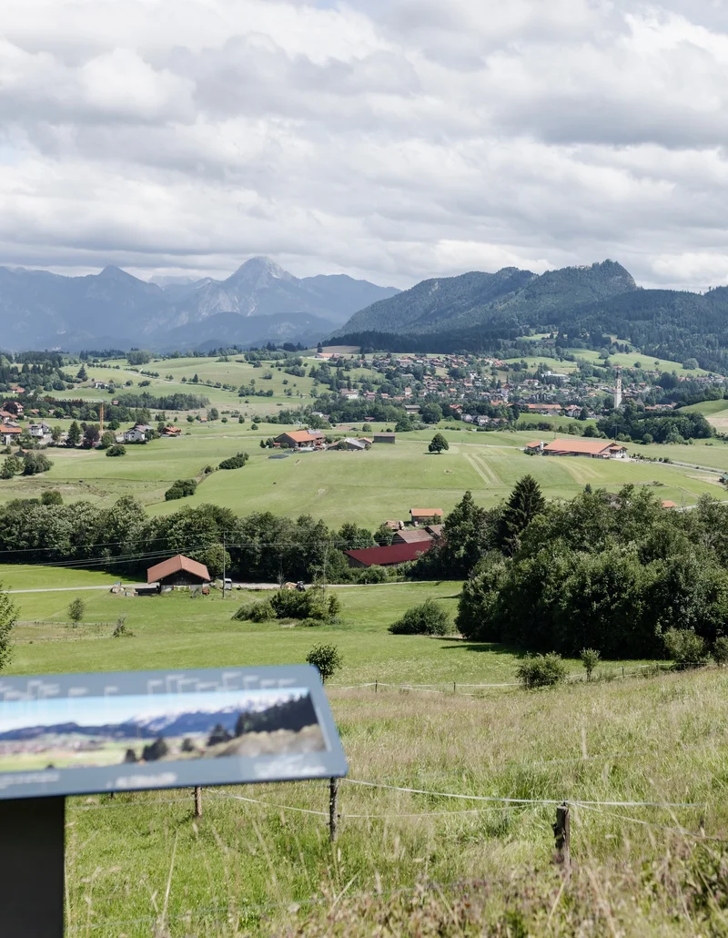 Panoramablick auf Pfronten mit Bergen im Hintergrund.