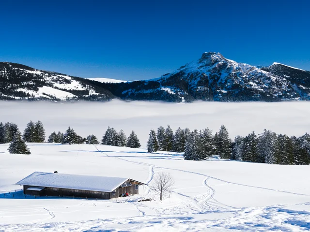 Eine idyllisch verschneite Bergkulisse bei Sonnenschein.