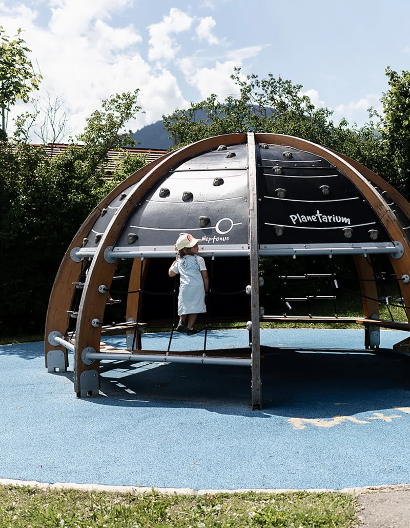 Ein Mädchen spielt auf einem Kuppel-Spielgerät.