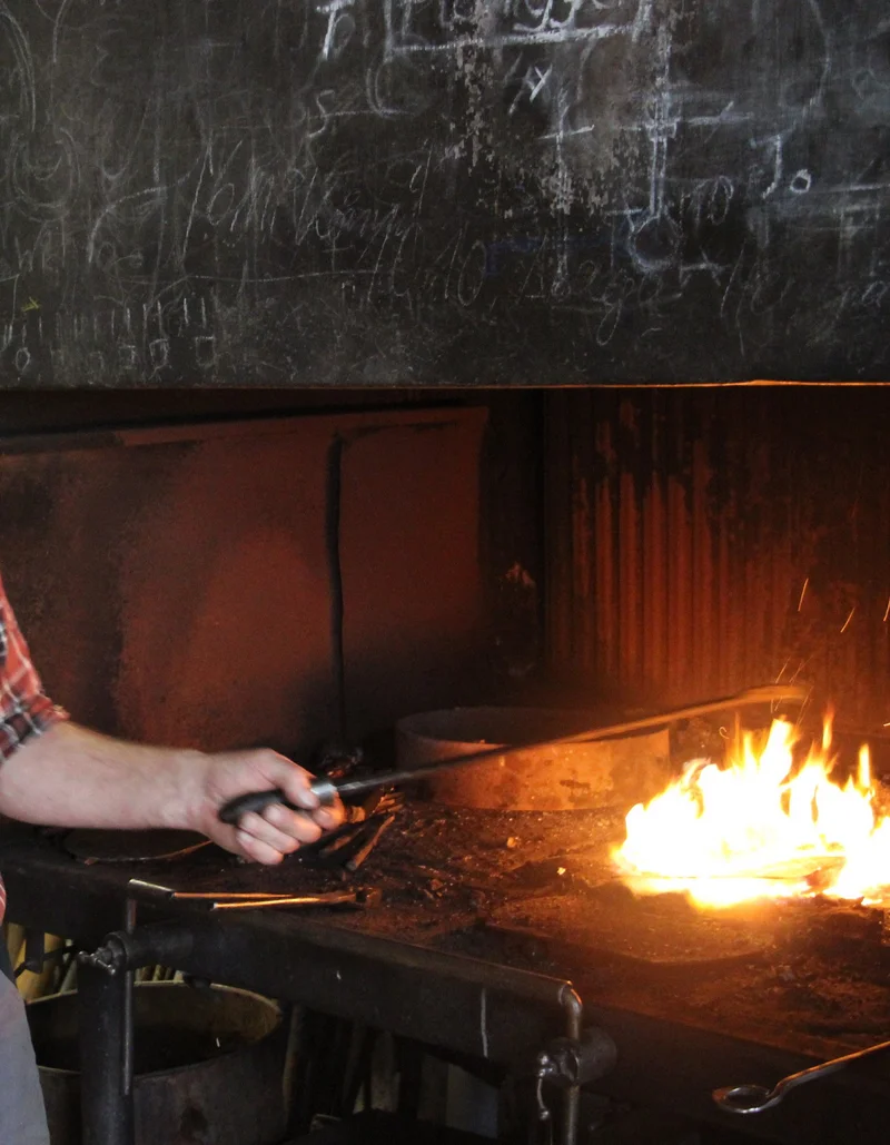 Ein Schmied beim Schmieden einer Schelle.