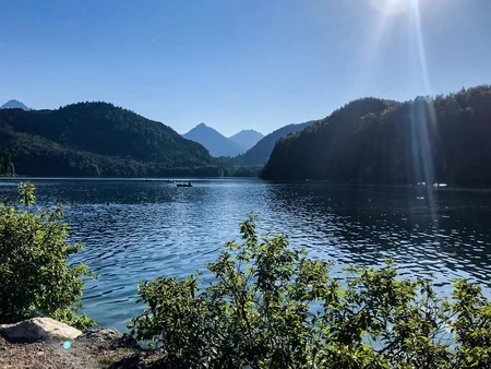 Sonniger Blick auf den Allgäuer Alpsee mit Bergen im Hintergrund.