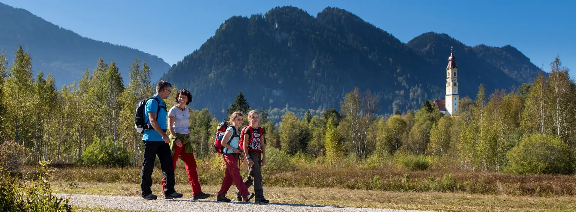 Eine Familie beim Spaziergang durch das sonnige Pfrontener Tal.