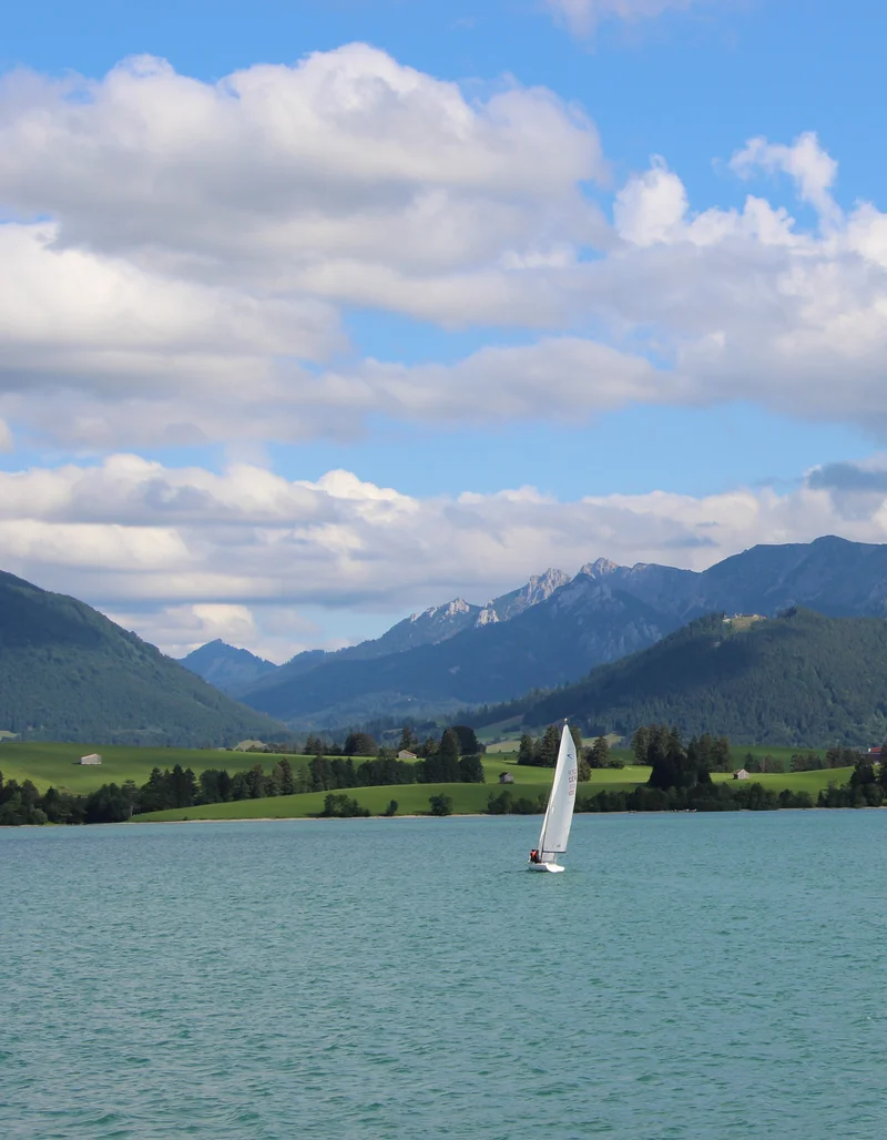 Blick über den Allgäuer Forgensee mit Bergen im Hintergrund.