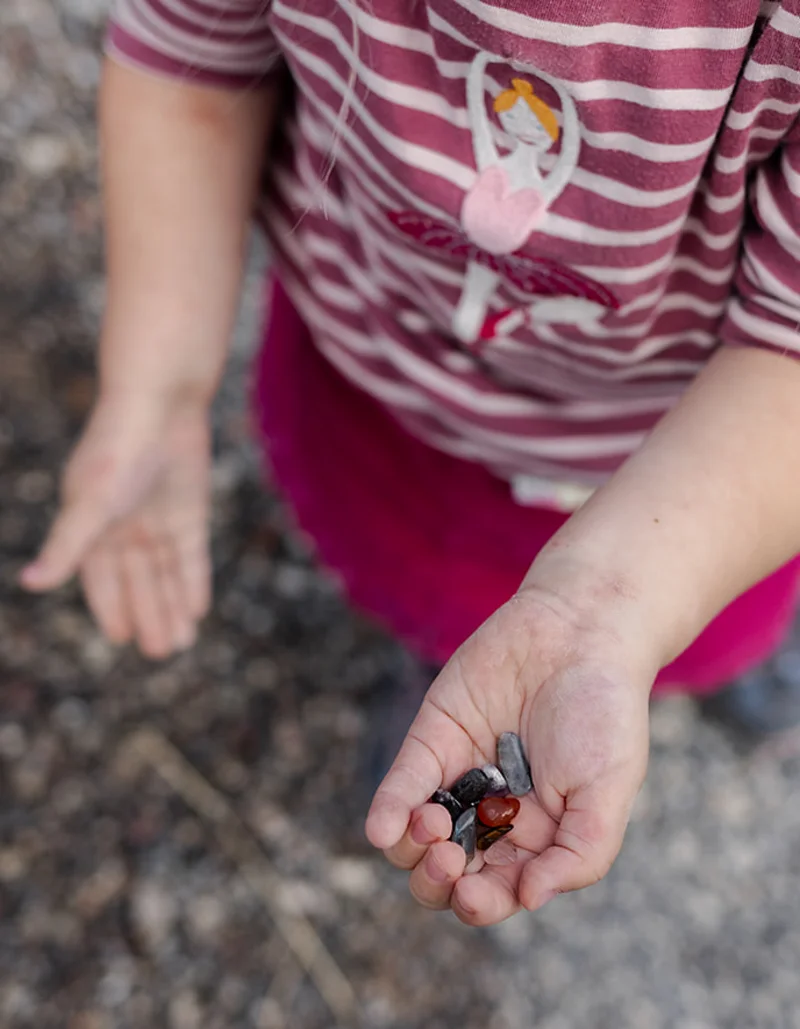 Kind hält bunte Steine in der Hand.