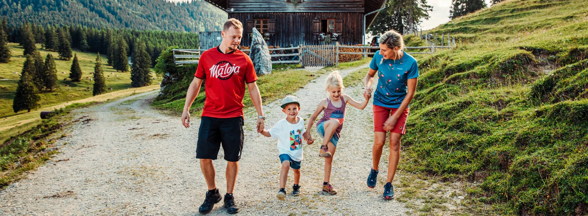 Eine Familie auf einem Wanderweg, im Hintergrund eine Hütte zum Einkehren.