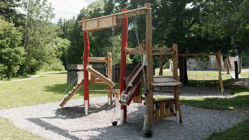 Ein Kind spielt auf einem hölzernen Spielgerüst.