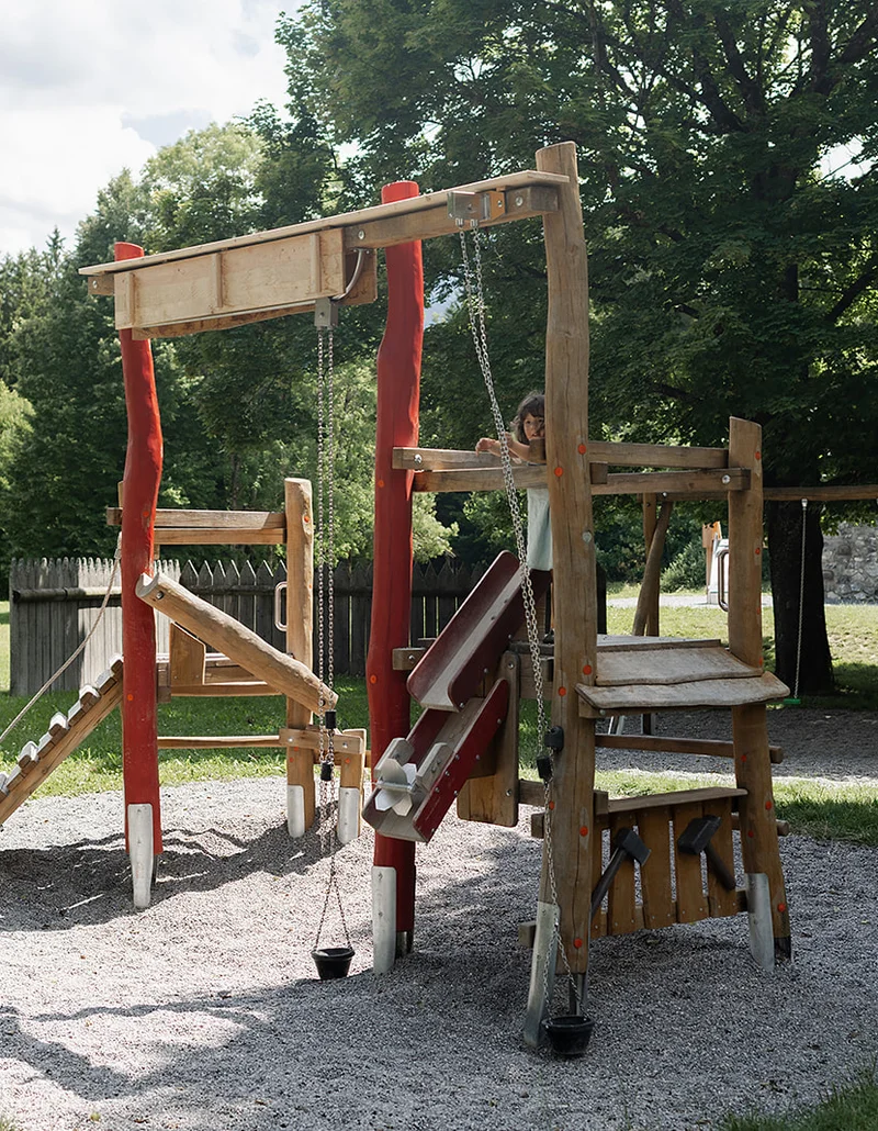 Ein Kind spielt auf einem hölzernen Spielgerüst.