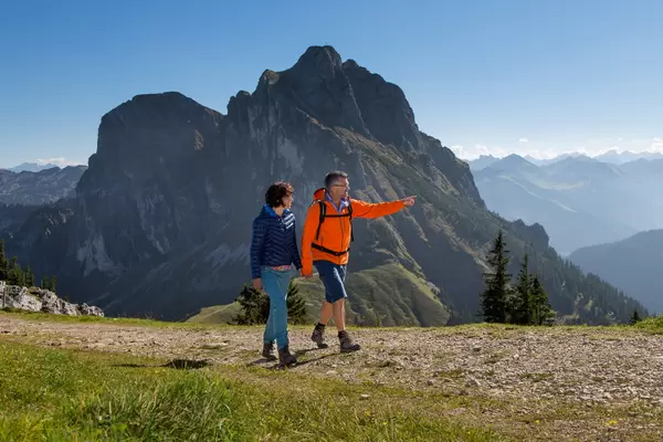 Wanderer auf einem sonnigen Weg auf dem Breitenberg in Pfronten mit einer imposanten Bergkulisse.