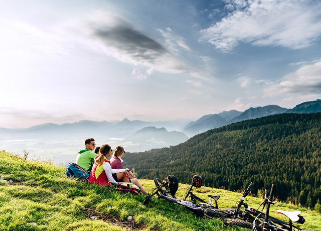 Eine Gruppe Mountainbiker genießt bei einer Pause den Ausblick auf das beeindruckende Bergpanorama.