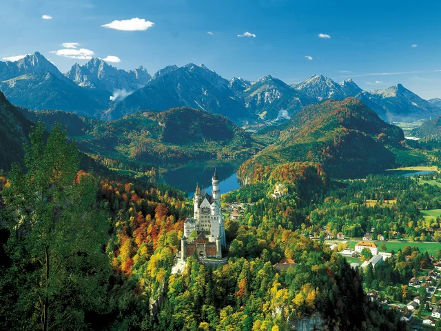Panoramablick auf das Schloss Neuschwanstein im Allgäu und die umliegende Bergkulisse.