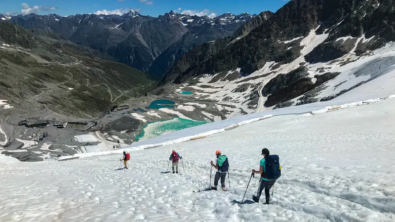 Wanderer inmitten einer schneebedeckten Berglandschaft bei der Alpenüberquerung.
