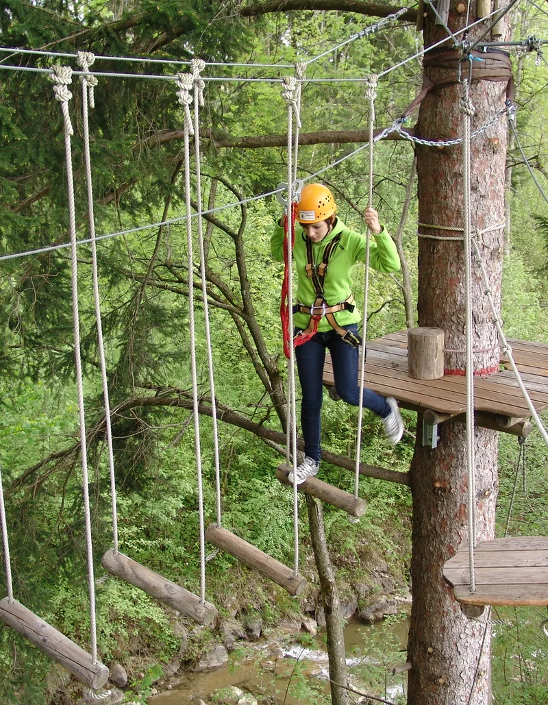 Eine Kletterin im Waldseilgarten Höllschlucht in Pfronten.