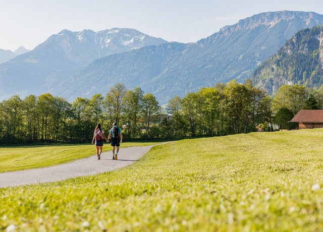 Wanderer im Tal mit Bergen im Hintergrund