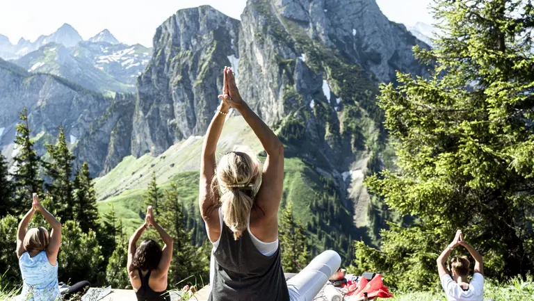 Eine Gruppe macht Yoga am Berg mit Blick auf die beeindruckende Bergkulisse.