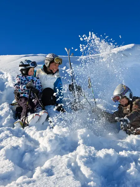 Wintervergnügen mit der ganzen Familie in Pfronten im Allgäu Eine Skifahrerfamilie sitzt bei sonnigem Wetter im Schnee und hat Spaß.