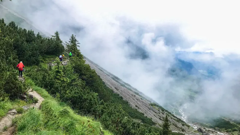 Wanderer auf einem schmalen Pfad inmitten einer alpinen Landschaft.