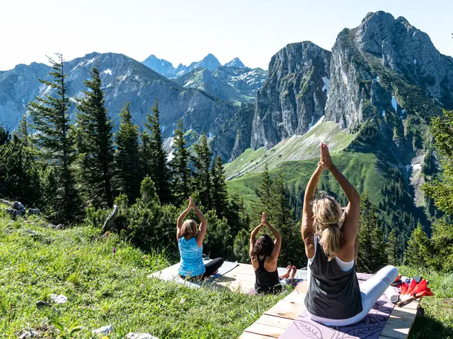 Eine Gruppe macht Yoga am Berg mit Blick auf die beeindruckende Bergkulisse.