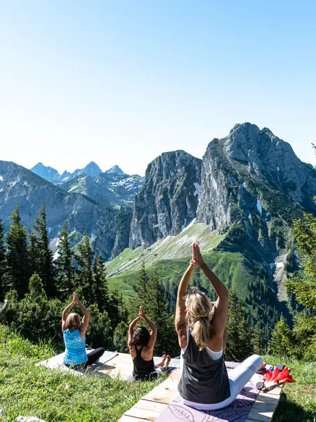 Eine Gruppe macht Yoga am Berg mit Blick auf die beeindruckende Bergkulisse.