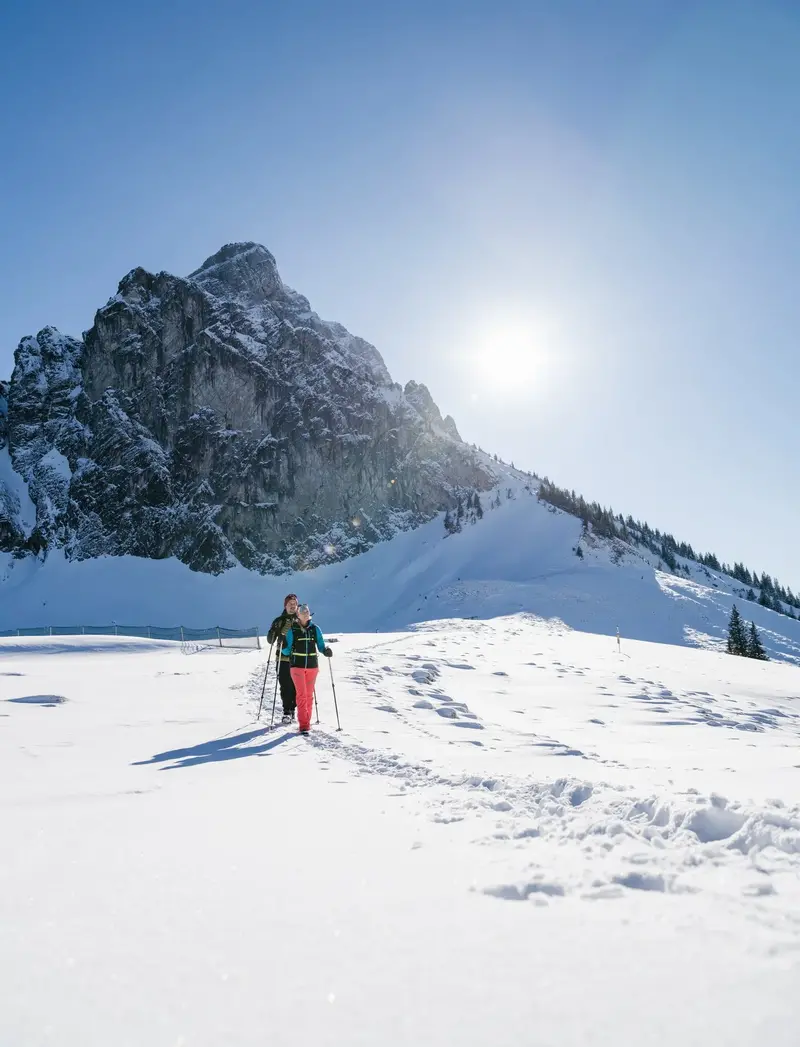 Wanderer auf verschneiten Wegen mit einem winterlichen Bergpanorama.