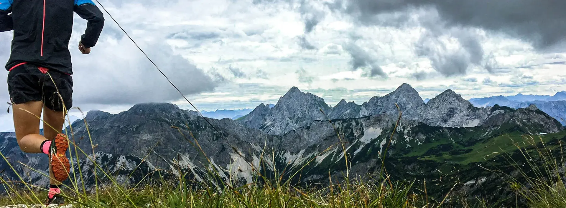 Eine Trailrunnerin auf einem Weg mit einer beeindruckenden Bergkulisse.