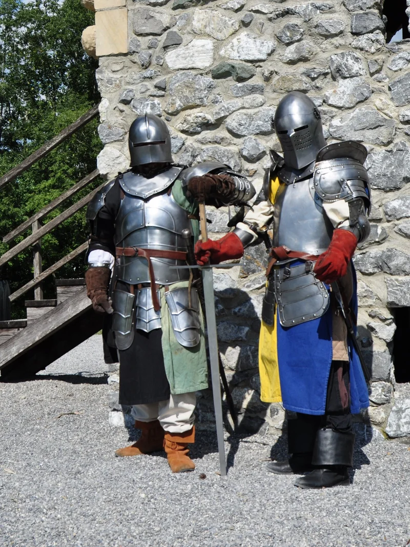 Zwei Ritter in Rüstung stehen nebeneinander vor einer Mauer auf dem Ritterspielplatz in Pfronten.