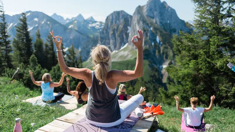 Eine Yoga-Gruppe macht Übungen vor einer schönen Bergkulisse.