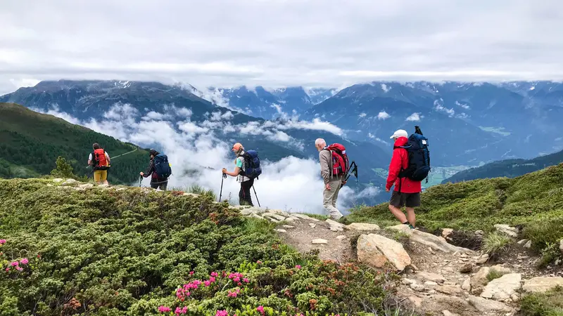 Eine Gruppe Wanderer auf einem Höhenweg mit beeindruckender Aussicht auf die Bergwelt.