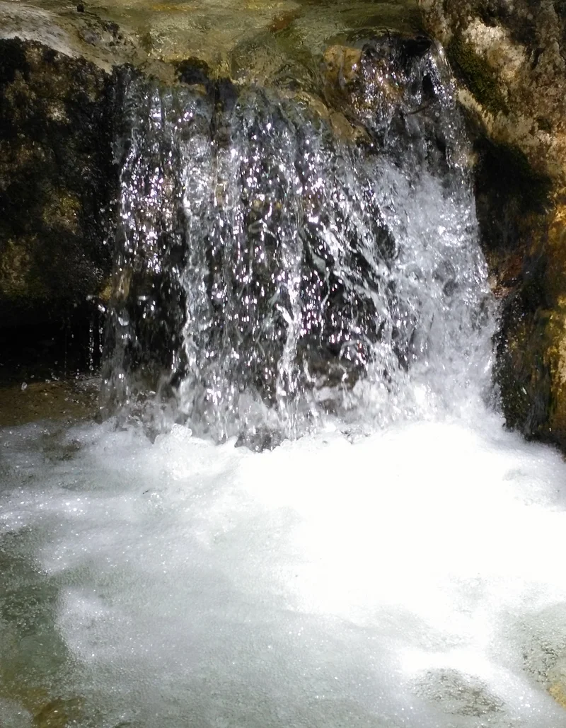 Ein kleiner Wasserfall, der von einer Steinmauer herabfließt
